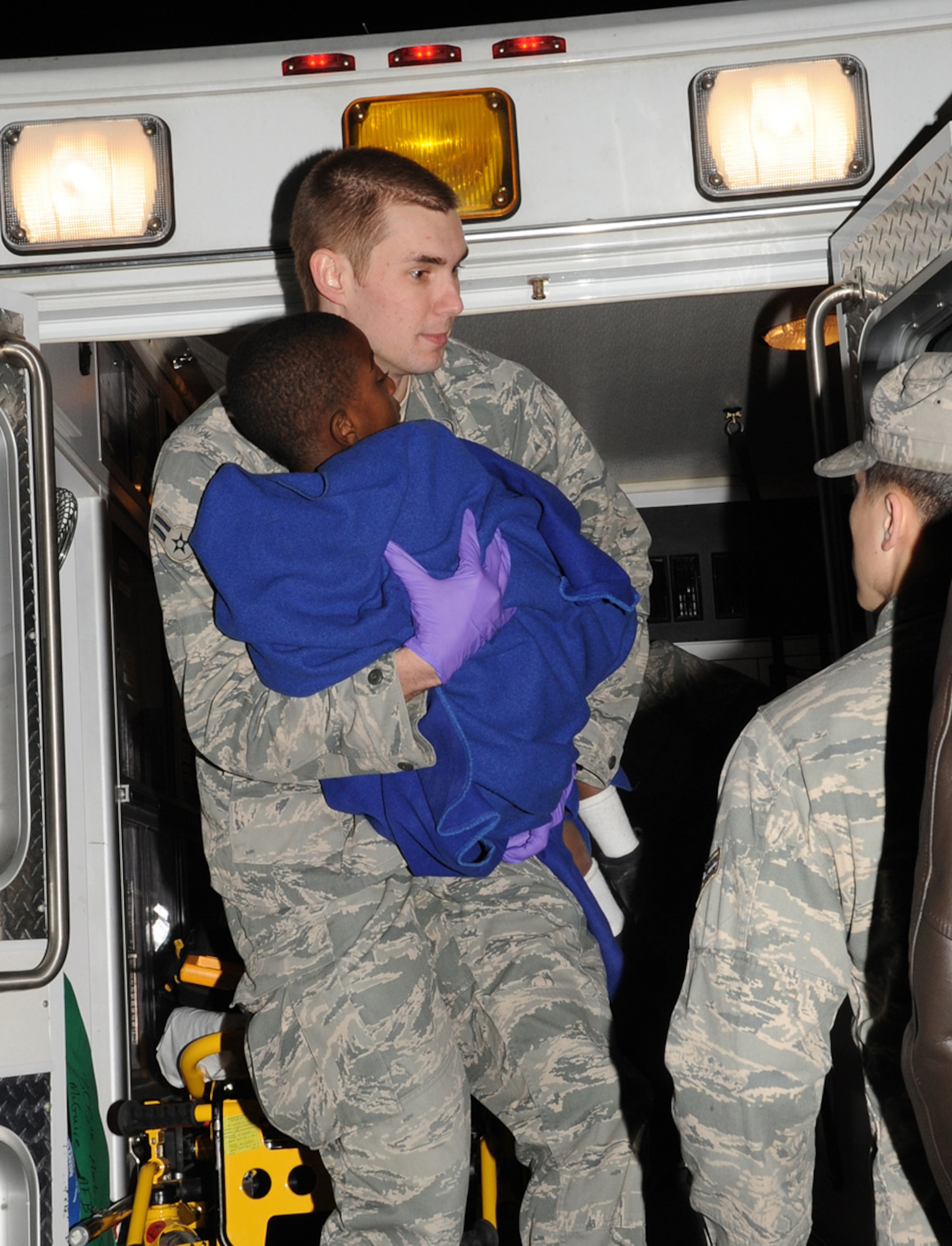 JOINT BASE MCGUIRE-DIX-LAKEHURST, N.J. – Airman 1st Class Brian Long, 87th Medical Group, carries a Haitian child off an ambulance at the passenger terminal here Saturday shortly after 44 survivors arrived from Port-au-Prince, Haiti. Airmen provided basic medical care to evacuees as needed and transported those with more serious injuries to a local hospital. (U.S. Air Force photo/Staff Sgt. Danielle Johnson)