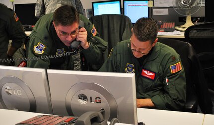 Lt. Col. Jon Thorpe and Maj. Todd Moore, assigned to the 618th Tanker Airlift Control Center at Scott Air Force Base, Ill., monitor the status of air mobility missions supporting relief efforts in Haiti, from the 618th TACC's Contingency Response Cell, Jan. 16.  618th TACC personnel have been working around-the-clock since Tuesday to support U.S. relief efforts in Haiti after a 7.0-magnitude earthquake struck the region. The 618th TACC's Contingency Response Cell, comprised of mission planners, managers and command-and-control personnel, is specifically dedicated to Air Mobility Command's involvement in Haiti relief operations, enabling other 618th TACC personnel to continue planning missions to support other U.S. operations worldwide, including in support of Operations Iraqi and Enduring Freedom. (U.S. Air Force photo/Capt. Justin Brockhoff) 