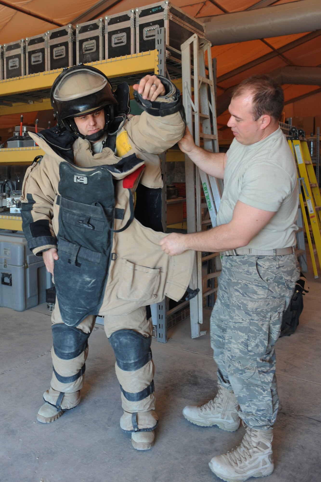 Staff. Sgt. Michael Duane, 379th Expeditionary Civil Engineering Squadron EOD craftsman helps Tech. Sgt. Neil Gertiser, also an EOD craftsman, don an EOD bomb suit at a non-disclosed Southwest Asia location, Jan. 14, 2010. The suit can withstand an explosion of five pounds of TNT at a distance of five feet. (U.S. Air Force photo/Tech. Sgt. Michelle Larche) [RELEASED]