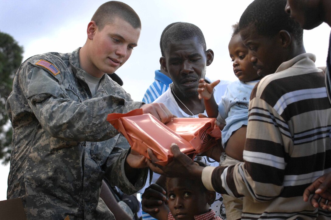 Army Spc. Brent Nailor of the 82nd Airborne Division’s 1st Squadron, 73rd Cavalry Regiment, passes out packaged meals to women and children in Port-au-Prince, Haiti, Jan. 16, 2010. The squadron established a forward operating base at an abandoned and damaged country club near the U.S. embassy. A survivor camp of thousands is situated near the base. DoD photo by Fred W. Baker III