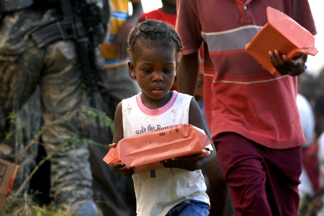 Women and children receive a humanitarian meal in Port-au-Prince, Haiti, Jan. 16, 2010. U.S. soldiers, assigned to the 82nd Airborne Division's 1st Squadron, 73rd Cavalry Regiment, passed out more than 2,500 meals during their first day on the ground at a forward operating base. 