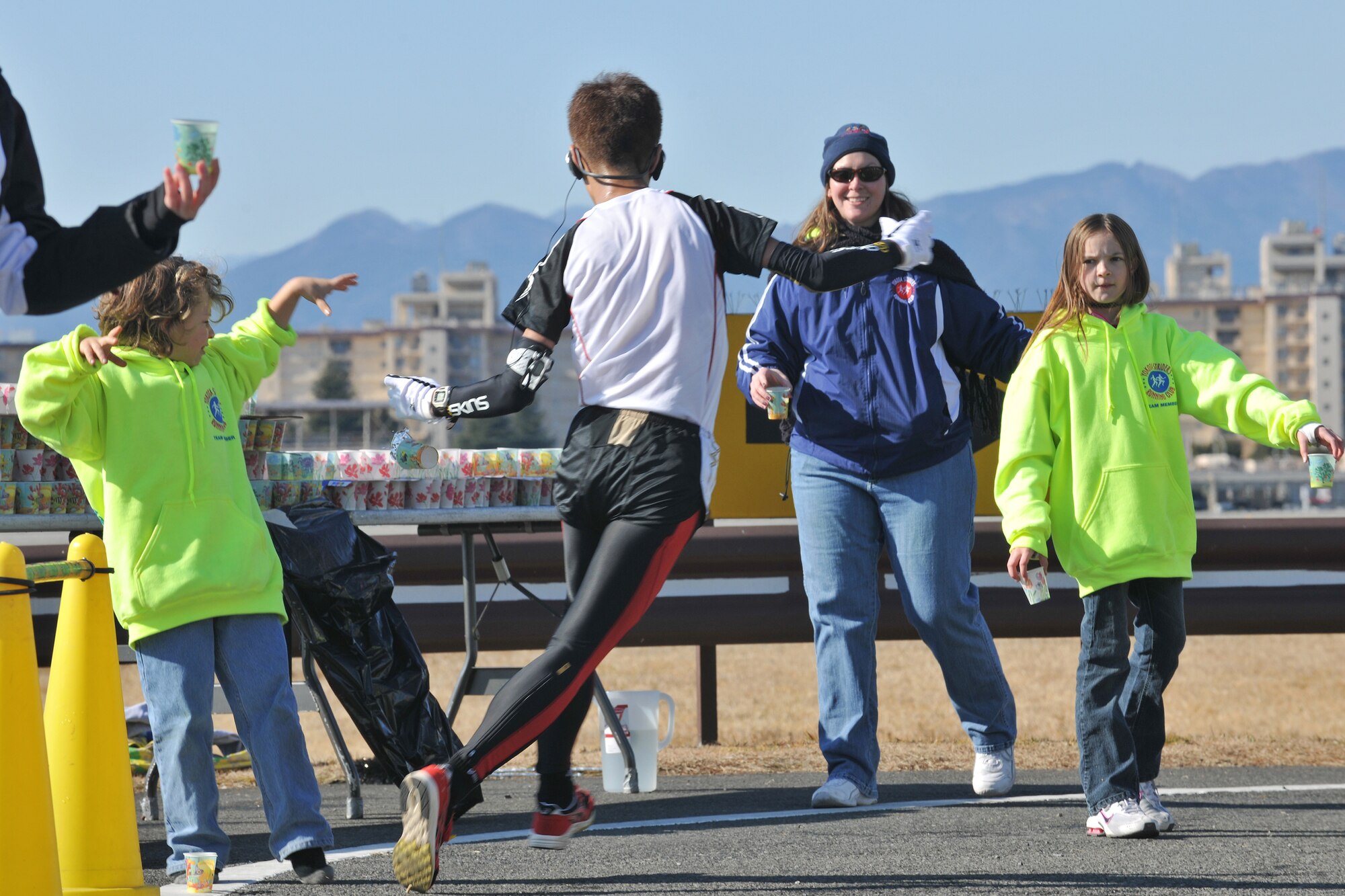 YOKOTA AIR BASE, Japan -- Yokota Striders Running Club held the 29th Annual Frostbite Race, Jan. 17.  Declan Denny (left), Yokota Elementary School 2nd grader, volunteers by offering cups of water to runners. (U.S. Air Force photo/Osakabe Yasuo) 
