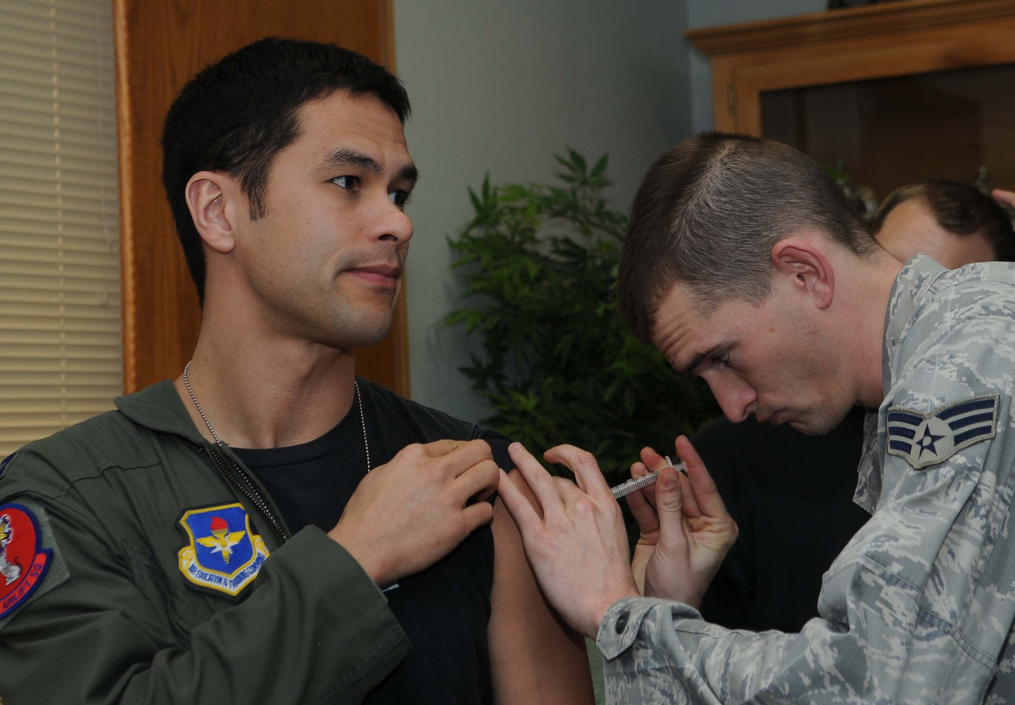 ALTUS AIR FORCE BASE, Okla.-- Capt. Corey Akiyama, 58th Airlift Squadron, receives his H1N1 immunization from Senior Airman Joel Boyd, 97th Medical Group, in order to depart for the humanitarian relief effort, Operation Unified Response.  Altus sent six Globemaster III to assist with the relief effort in Haiti by delivering supplies such as food and water.  Altus aircrews will be staged out of Pope AFB, N.C. (U.S. Air Force photo/Senior Airman Leandra D. Hernandez)