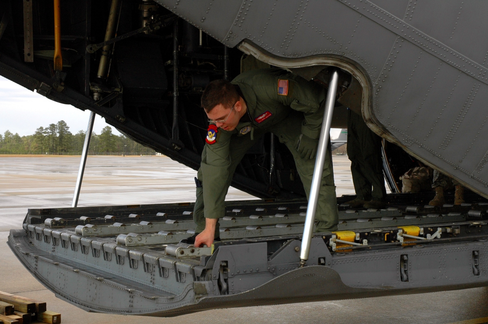DYESS AIR FORCE BASE, Texas -- Staff Sgt. Henry Morgan, 317th Airlift Group, secures roller tracks to the back of a C-130 Hercules at an East Coast Air Force Base Jan. 17. The C-130 crew of six departed Dyess Air Force Base to support relief efforts following the 7.0-magnitude earthquake that devistated the Caribbean nation Jan. 14. The Air Force's airlift capability enables the United States to respond immediately to any disaster domestically or worldwide. We are the only country with an aircraft fleet capable of providing this type of response.