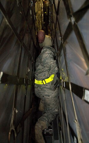 Airman Curtis Moore, front, and Airman 1st Class Jason Cox squeeze between  pallets of food aboard a McChord AFB C-17 on the Charleston AFB flightline Jan. 18. Little space between each pallet presented difficulty for the Airmen in securing them to the cargo floor. Airmen Curtis and Cox are air transportation journeyman with the 437th Aerial Port Squadron. (U.S. Air Force photo/Staff Sgt. Daniel Bowles)