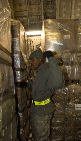 Senior Airman Anel Dominique calls for help from another Airman after attempting to chain down a pallet of food to a McChord AFB C-17 on the Charleston AFB flightline Jan. 18. Sixteen pallets were loaded on the aircraft with little space between each one, presenting difficulty in securing them to the cargo floor. Airman Dominique is an air transportation journeyman with the 437th Aerial Port Squadron. (U.S. Air Force photo/Staff Sgt. Daniel Bowles)