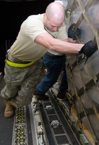 Airman 1st Class Jason Cox strains to push a pallet of Meals-Ready-to-Eat onto a McChord AFB C-17 on the Charleston AFB flightline Jan. 18. The pallet of food weighed approximately 9,000 pounds and was one of seven loaded for shipment to victims of the recent earthquake in Haiti. Airman Cox is an air transportation journeyman with the 437th Aerial Port Squadron. (U.S. Air Force photo/Staff Sgt. Daniel Bowles)