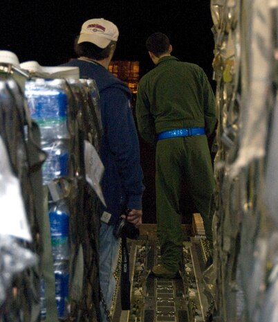 Senior Airman Anthony Jimenez, back, monitors the movement of a Tunner 60K Loader as it is positioned behind a McChord C-17 on the Charleston AFB flightline Jan. 18. The industrial loading vehicle must be carefully positioned to allow expeditious transfer of cargo pallets onto aircraft. Airman Jimenez is a loadmaster with the 10th Airlift Squadron, McChord AFB, Wash. (U.S. Air Force photo/Staff Sgt. Daniel Bowles)
