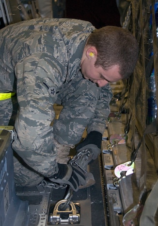 Airman Curtis Moore chains down a pallet of bottled water to the cargo floor of a McChord AFB C-17 on the Charleston AFB flightline Jan. 18. Chains are used in addition to locks on the cargo floor to inhibit any movement and shifting of pallets during flight. Airman Moore is an air transportation apprentice with the 437th Aerial Port Squadron ramp services section. (U.S. Air Force photo/Staff Sgt. Daniel Bowles)