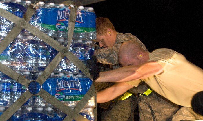 Airmen 1st Class James Harrison, left, and Jason Cox push a pallet of bottle water weighing several thousand pounds from a Tunner 60K Loader onto a McChord AFB C-17 on the Charleston AFB flightline Jan. 18. The water was loaded as part of the first of many missions to leave from Charleston AFB carrying food and water to aid victims of the recent earthquake in Haiti. Airmen Harrison and Cox are air transportation journeymen with the 437th Aerial Port Squadron. (U.S. Air Force photo/Staff Sgt. Daniel Bowles)