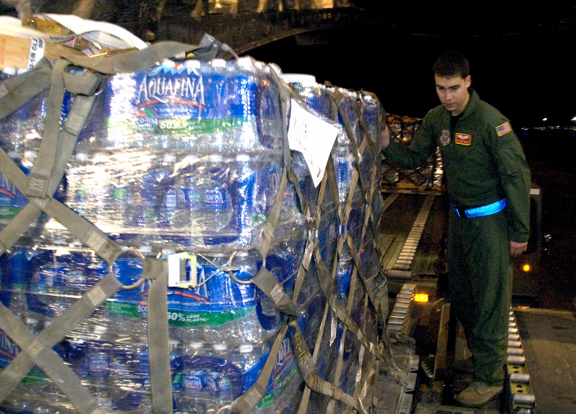 Senior Airman Anthony Jimenez prepares to push a pallet of bottled water on a McChord C-17 on the Charleston AFB flightline Jan. 18. The pallet contained more than 4,000 bottles of water and were shipped to Haiti as part of the humanitarian relief effort to aid victims of the recent earthquake. Airman Jimenez is a loadmaster with the 10th Airlift Squadron, McChord AFB, Wash. (U.S. Air Force photo/Staff Sgt. Daniel Bowles)