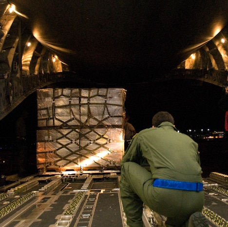 Senior Airman Anthony Jimenez, front, monitors the movement of a Tunner 60K Loader as it is positioned within inches of a McChord C-17 on the Charleston AFB flightline Jan. 18. The industrial loading vehicle must be carefully positioned to allow expeditious transfer of cargo pallets onto aircraft. Airman Jimenez is a loadmaster with the 10th Airlift Squadron, McChord AFB, Wash. (U.S. Air Force photo/Staff Sgt. Daniel Bowles)