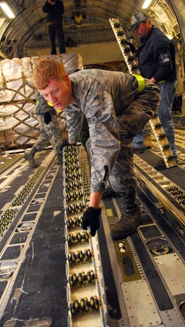 Airman 1st Class James Harrison, front, and Timothy Chinners swap out rollers on the cargo floor of a McChord AFB C-17 on the Charleston AFB flightline Jan. 18. The rollers were replaced with bidirectional rollers to allow quicker loading of 16 pallets of food and water destined for victims of the recent earthquake in Haiti. Airman Harrison is an air transportation journeyman and Mr. Chinners is a ramp loading supervisor, both are with the 437th Aerial Port Squadron. (U.S. Air Force photo/Staff Sgt. Daniel Bowles)