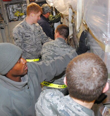 Air transportation specialists with the 437th Aerial Port Squadron work together to load a pallet of food onto a McChord AFB C-17 on the Charleston AFB flightline Jan. 18. The pallet of food  part of a 116,000 pound shipment of food and water to aid victims of the recent earthquake in Haiti. (U.S. Air Force photo/Staff Sgt. Daniel Bowles)