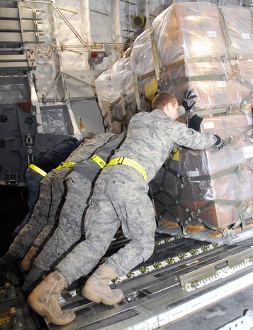 Air transportation specialists with the 437th Aerial Port Squadron work together to load a pallet of food onto a McChord AFB C-17 on the Charleston AFB flightline Jan. 18. The pallet of food  part of a 116,000 pound shipment of food and water to aid victims of the recent earthquake in Haiti. (U.S. Air Force photo/Staff Sgt. Daniel Bowles)