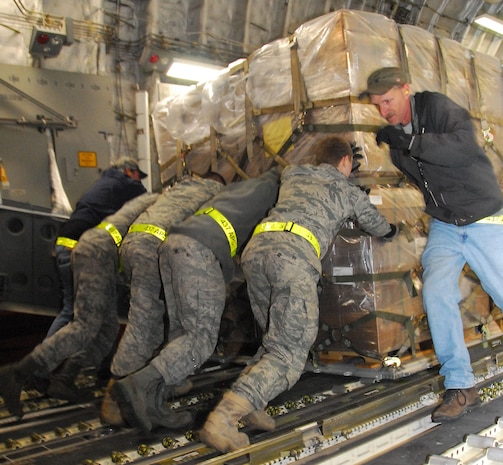 Lawrence Curtis runs to assist fellow air transportation specialists push an enormous pallet of Meals-Ready-to-Eat onto a McChord AFB C-17 on the Charleston AFB flightline Jan. 18. The pallet of food was loaded as part of the first humanitarian mission to leave Charleston AFB laden with food and water to aid victims of the recent earthquake in Haiti. Mr. Curtis is a work leader with the 437th Aerial Port Squadron ramp services section. (U.S. Air Force photo/Staff Sgt. Daniel Bowles)