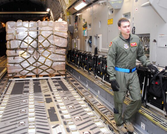 Senior Airman Anthony Jimenez moves toward the front of a McChord AFB C-17 as Airmen with the 437th Aerial Port Squadron maneuver a pallet of Meals-Ready-to-Eat into position Jan. 18 on the Charleston AFB flightline. The MREs were prepared and loaded by the 437 APS aboard the aircraft as part of the first humanitarian mission to leave Charleston AFB laden with food and water to aid victims of the recent earthquake in Haiti. Airman Jimenez is a loadmaster with the 10th Airlift Squadron, McChord AFB, Wash. (U.S. Air Force photo/Staff Sgt. Daniel Bowles)