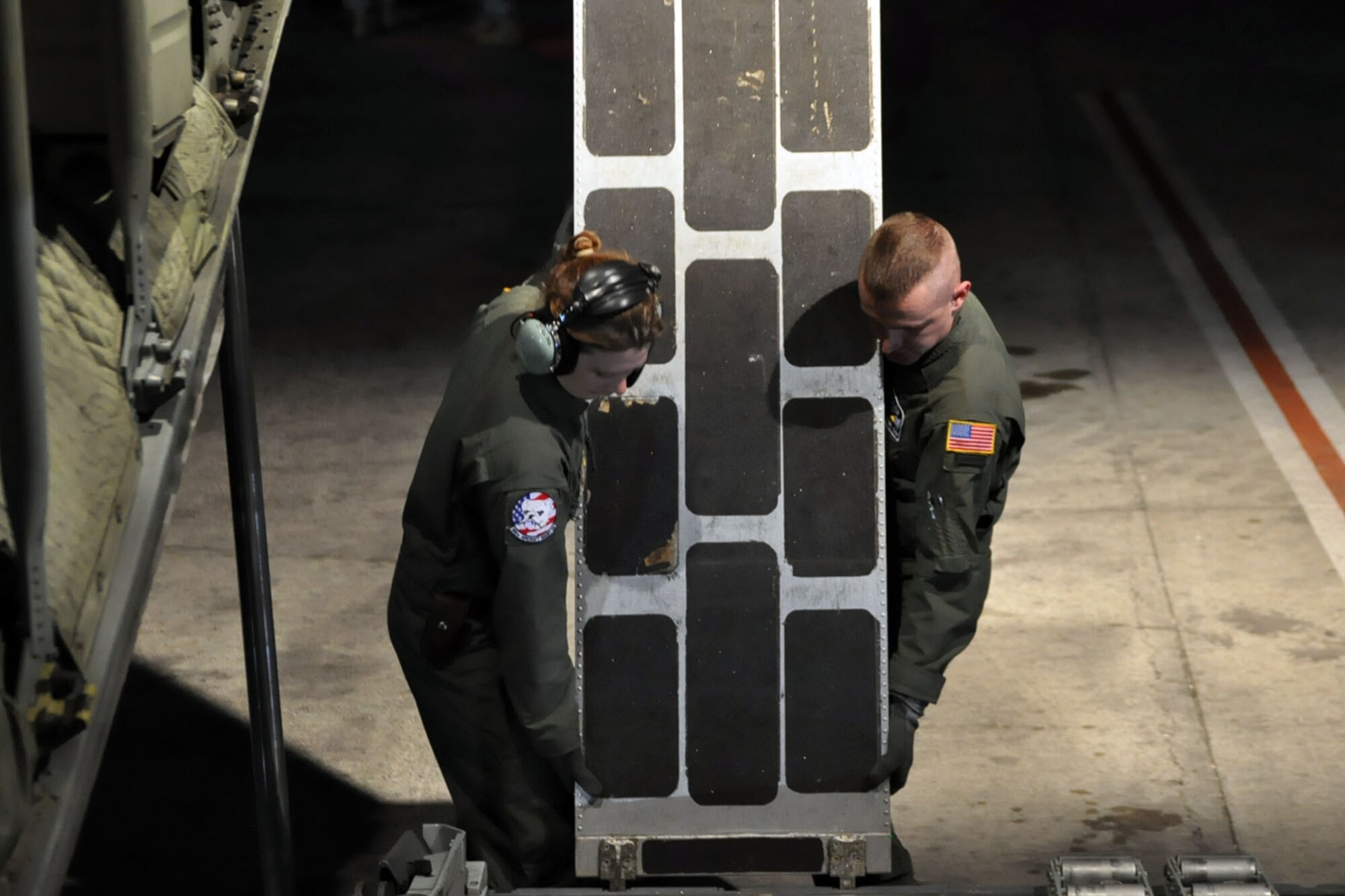 PORT-AU-PRINCE INTERNATIONAL AIRPORT, Haiti -- Air Force Reserve Senior Airman Jessica Strumbly, a crew chief with the 910th Aircraft Maintenance Squadron, and Staff Sgt. Michael Culp, a loadmaster with the 773rd Airlift Squadron, remove a loading ramp from the rear cargo platform of a C-130H Hercules tactical cargo transport aircraft on the tarmac, here, January 18. The Citizen Airmen are part of a 12-person crew assigned to the 910th Airlift Wing, based out of Youngstown Air Reserve Station, Ohio, that just delivered a group of U.S. Military medical personnel and supplies as part of the relief effort to the Haitian people in the aftermath of the massive earthquake that devastated Port-au-Prince and the surrounding areas last week. The medical personnel, consisting of U.S. Army and Air Force Servicemembers were flown, by the 910th's C-130, to Haiti from Soto Cano Air Base, Honduras. The 910th currently has three aircraft, crews of more than 30 personnel flying relief effort missions and a myriad of Citizen Airmen working at YARS to provide home station support to the crews. The 910th Airlift Wing stands ready to provide airlift capabilities to the massive humanitarian effort as long as needed by mission requirements.