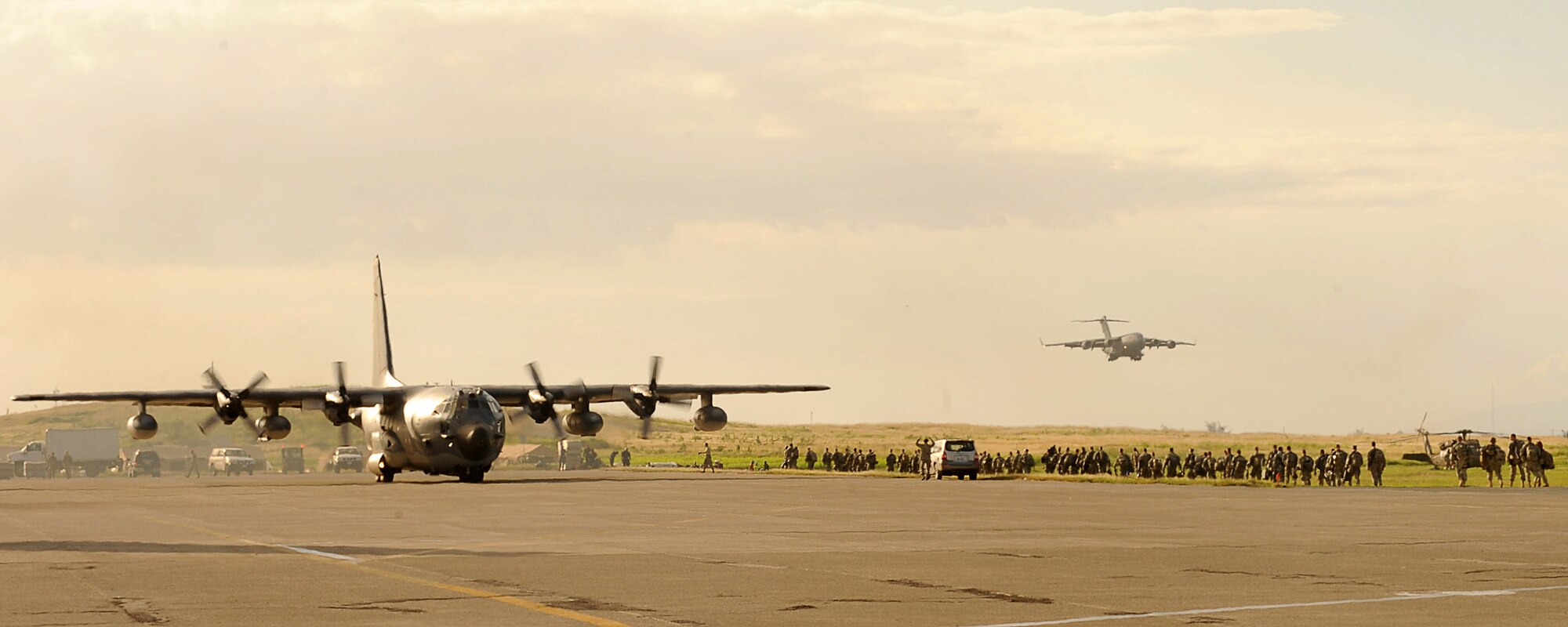 A C-130 Hercules taxies on the flightline as a group of Soldiers from the 82nd Airborne Division, Ft. Bragg, N.C., head to a staging area. In the background, C-17 Globemaster III prepares to land at the Port-au-Prince International Airport, Haiti, Jan. 16, 2010. Both aircraft are assigned to Air Mobility Command. Since Jan. 13, AMC has delivered more than 1,600 tons of supplies as part of Operation Unified Response. AMC aircraft and personnel continue to support the international effort to increase the velocity with which aid is flowing to those in need earthquake relief
operation for the country of Haiti. (USAF Photo/Staff Sgt. Chad Chisholm)
