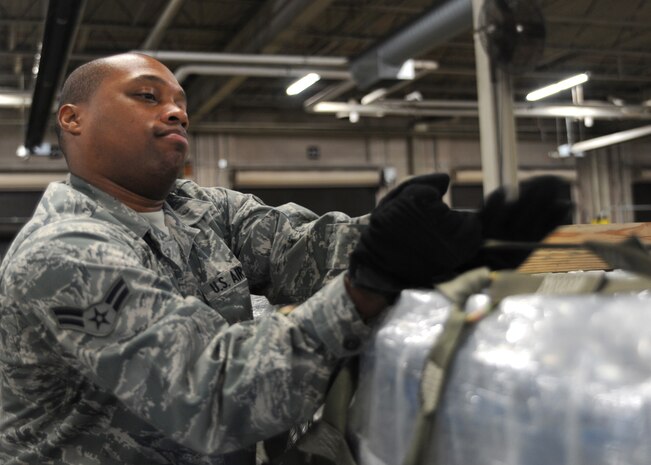 Airman 1st Class John Burks secures a pallet of water on Charleston AFB, Jan. 19. Air Mobility Command is responding with all necessary forces and equipment to aide the humanitarian relief efforts in Haiti. Airman Burks is a ramp services apprentice with the 437th Aerial Port Squadron. (U.S. Air Force photo/Senior Airman Katie Gieratz)(RELEASED)