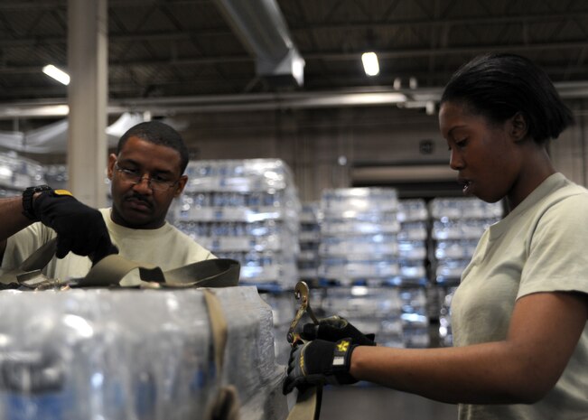 Staff Sgt. Denny Garrison and Senior Airman Veronica Garrison tie down bottled water to a pallet on Charleston AFB, Jan. 19. The water is being sent to Haiti to assist in the humanitarian relief effort. Sergeant Garrison is a cargo services supervisor and Airman Garrison is a ramp services journeyman, both are with the 437th Aerial Port Squadron. (U.S. Air Force photo/Senior Airman Katie Gieratz)(RELEASED)
