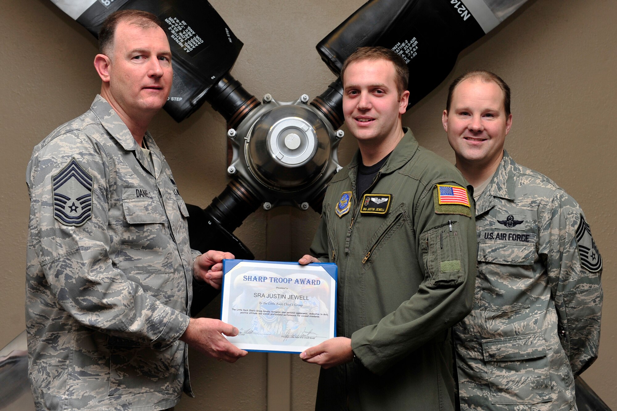 Chief Master Sgt. Jimmy Daniels, 19th Force Support Squadron superintendent, and Chief Master Sgt. Gregg Kollbaum, 53rd Airlift Squadron superintendent, present Senior Airman Justin Jewell, 53rd AS flight engineer, the Chief Sharp Troop Award Jan. 19 at Hangar 1080. Among other accomplishments, Senior Airman Jewell volunteered up as self-aid-buddy-care instructor, training eight Airmen to be Operation Iraqi Freedom deployment qualified. (U.S. Air Force photo by Airman 1st Class Lausanne Pacheco)