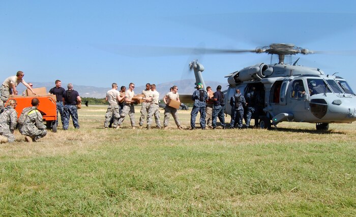 Soldiers and Sailors work side by side to move Meals Ready to Eat to awaiting Navy HH-60 helicopters that are transporting the supplies to distribution sites around Haiti in Port-au-Prince, Haiti, Jan. 18, 2010. The Soldiers are from the 82nd Airborne Division Fort Bragg, N.C., and the Sailors are assigned to the aircraft carrier USS Carl Vinson. (U.S. Air Force photo/Master Sgt. Sean P. Houlihan)