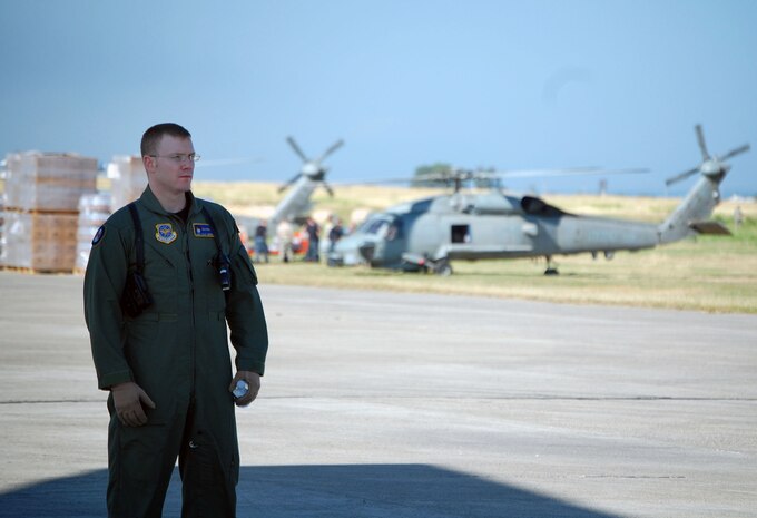 Staff Sgt. Clay Greenwell secures a C-17 Globemaster III from McChord AFB, Wash., as nearly 40,000 bottles of water and 30,000 Meals Ready to Eat are downloaded on 16 pallets on the flightline in Port-au-Prince, Haiti, Jan. 18, 2010. Sergeant Greenwell is an Air Force Phoenix Raven specializing in in-flight and plane-side security at austere global locations. (U.S. Air Force photo/Master Sgt. Sean P. Houlihan)