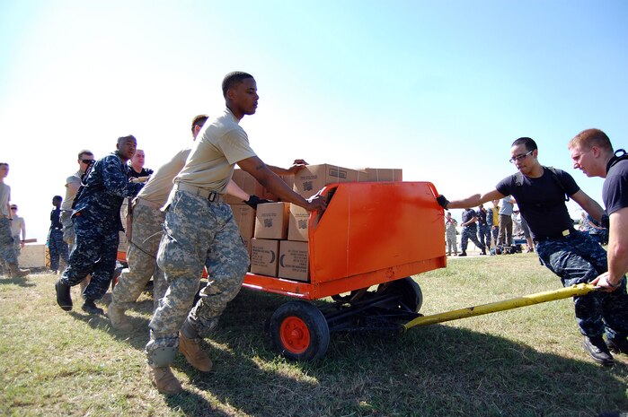Soldiers and Sailors work side by side to move Meals Ready to Eat to awaiting Navy HH-60 helicopters that are transporting the supplies to distribution sites around Haiti in Port-au-Prince, Haiti, Jan. 18, 2010. The Soldiers are from the 82nd Airborne Division Fort Bragg, N.C., and the Sailors are assigned to the aircraft carrier USS Carl Vinson. (U.S. Air Force photo/Master Sgt. Sean P. Houlihan)