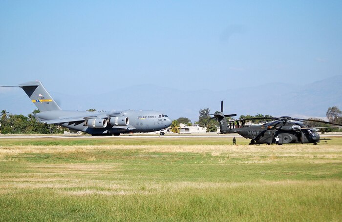 A C-17 Globemaster III from Charleston AFB taxis past a Navy helicopter at Port-au-Prince, Haiti, with relief supplies for U.S. service members and Haitian residents affected by the Jan. 12 7.0-magnitude earthquake Jan. 18, 2010.  Charleston AFB is the Air Force?s air operations hub for all C-17 relief effort flights. (U.S. Air Force photo/Master Sgt. Sean P. Houlihan)