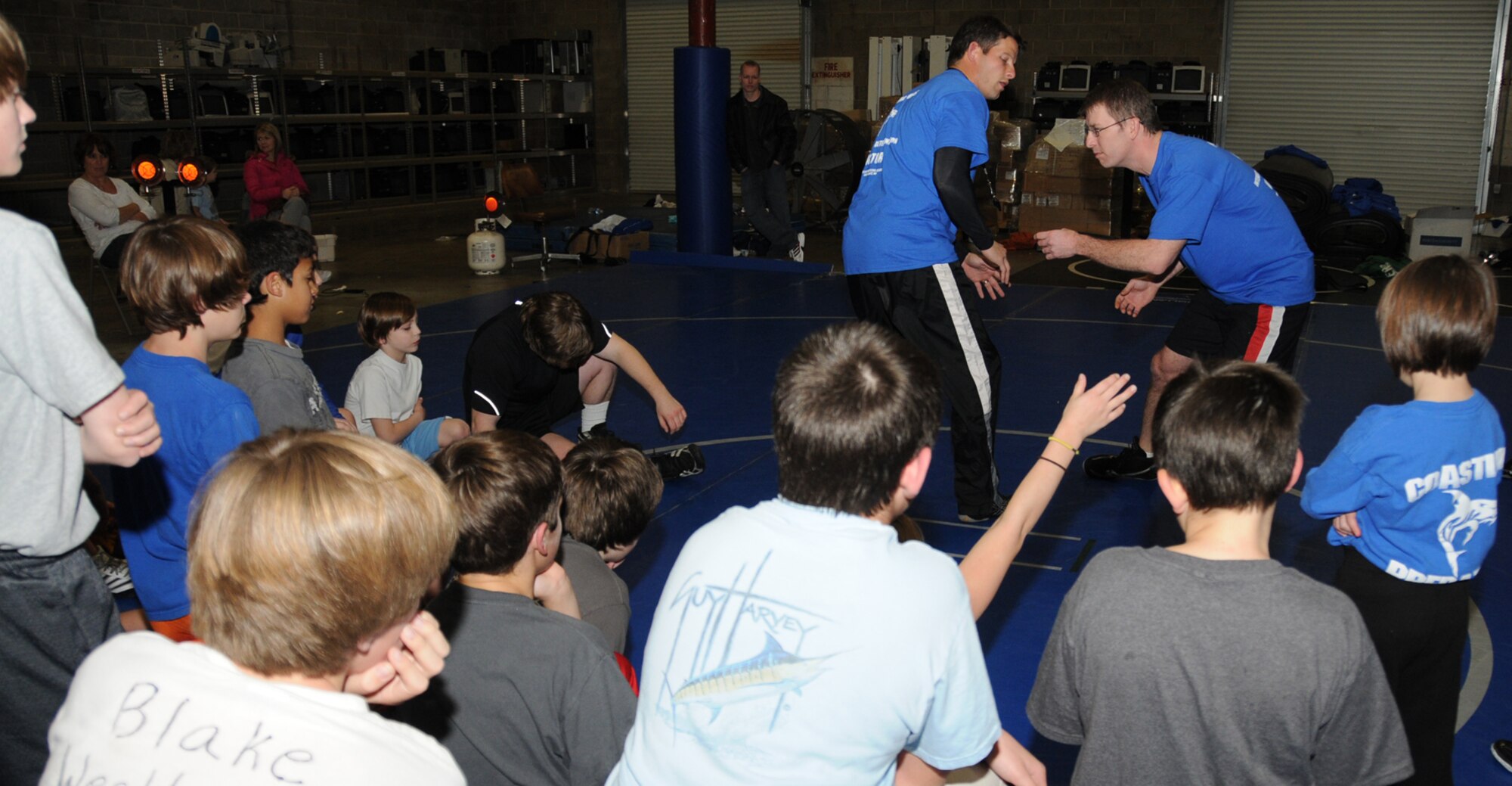 Grady Brown, left, and Mike Benca demonstrate a double leg takedown at practice Jan. 12.  Brown, head coach for the Ocean Springs High School wrestling team and Coastline Predators Wrestling Academy, teaches math at Ocean Springs Junior High School.  Benca, an assistant coach, is a cardiologist at Keesler Medical Center.    (U.S. Air Force photo by Kemberly Groue)