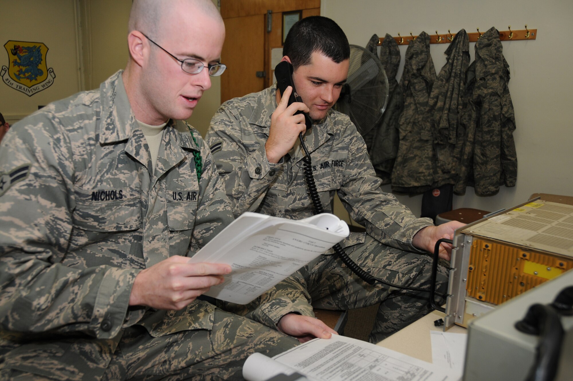 Airman 1st Class James, left, and A1C Lawrence Nichols train together on an AN/GRC 171 radio Jan. 7 in Jones Hall. The brothers are in one of the final legacy ground radio courses in the 338th TRS.  The new radio frequency transmission systems apprentice maintenance course that began Jan. 5 combines the ground radio and the satellite, wideband and telemetry systems courses.  (U.S. Air Force photo by Kemberly Groue)