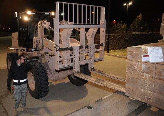 CANNON AIR FORCE BASE, N.M.-- Staff Sgt. Blake Jorgenson, 27th Special Operations Logistics Readiness Squadron, guides a forklift driven by Airman 1st Class Greg Strauch, 27th SOLRS, to one of the 11 pallets of MRE's. Each bundle weighs about 1,100 lbs and is being sent to Haiti. (U.S. Air Force photo by Airman 1st Class Maynelinne De La Cruz) 
