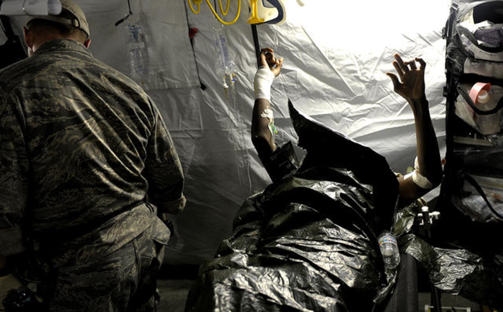 A U.S. Air Force medical technician from Air Force Special Operations Command at Hurlburt Field, Fla., checks on Haitian patients in a field clinic in Port au Prince, Haiti, Jan. 16, 2010. The patients were injured by the devastating earthquake that struck the city Jan. 12, 2010. (U.S. Air Force photo by Master Sgt. Russell E. Cooley IV/Released)