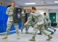 HANSCOM AIR FORCE BASE, Mass. -- 66th Security Forces Squadron instructors (from left) Tech. Sgt. Wayne Griggs, Airman 1st Class Ronald Ashley and Senior Airman Derek Fox hold protective pads as 1st Lt. Brian Pedroza, 635th Electronic Systems Squadron; 1st Lt. Lex Parker, 951st Electronic Systems Group and 2nd Lt. Joven Mercado, 850th Electronic Systems Group, practice closed mode weapon side strikes during a 66 SFS augmentee class on Jan. 12.  (U.S. Air Force photo by Mark Wyatt)