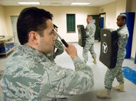 HANSCOM AIR FORCE BASE, Mass. -- At a 66th Security Forces Squadron augmentee training class, held Jan. 12, 1st Lt. Lex Parker (left), 951st Electronic Systems Group, prepares to execute an open mode reaction side strike. Tech. Sgt. Wayne Griggs and Airman 1st Class Ronald Ashley (right), 66 SFS, hold protective padding and provide students with feedback.  (U.S. Air Force photo by Mark Wyatt)