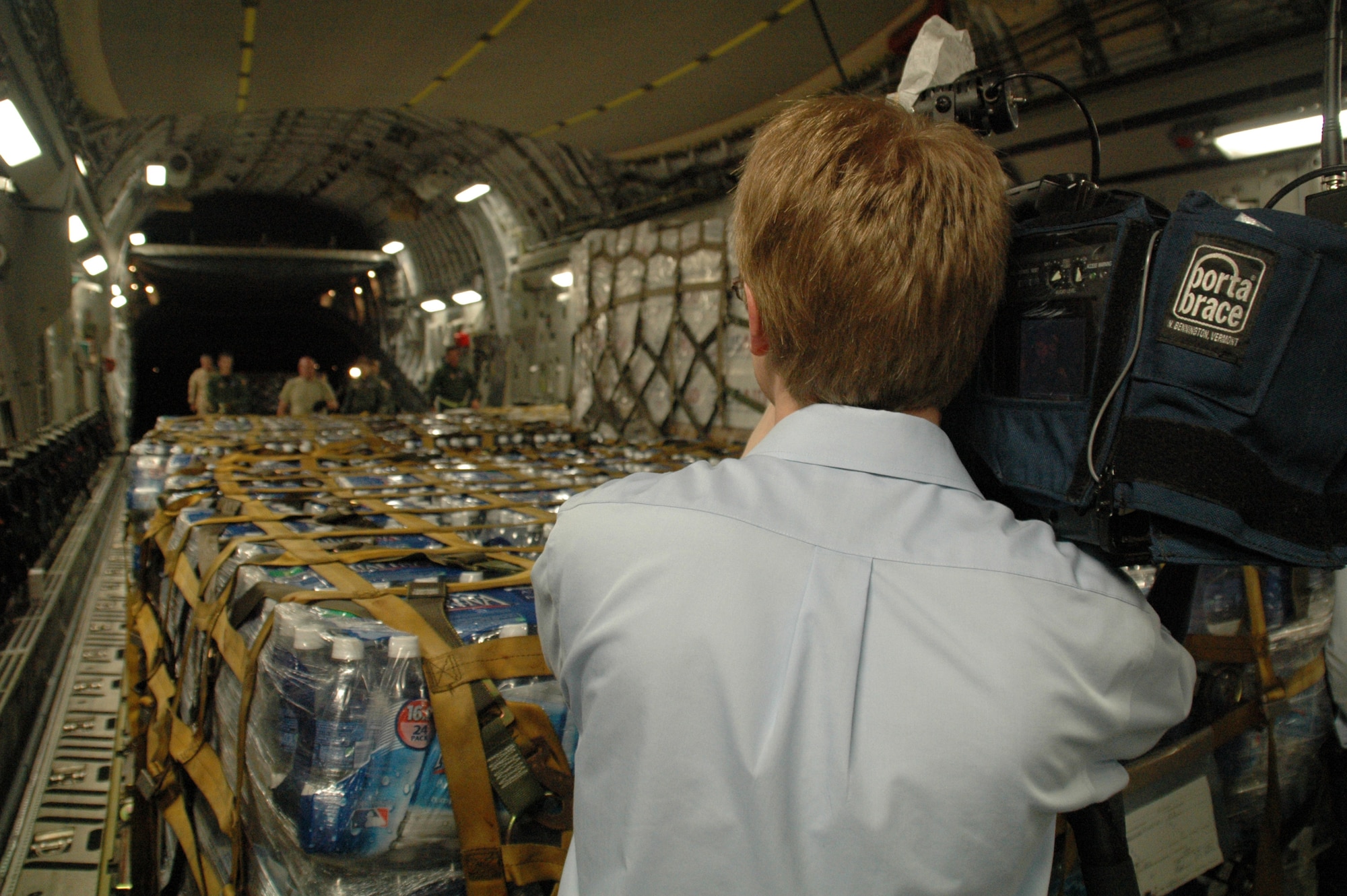 A reporter from WIS News 10, Columbia, S.C. observes the offload of humanitarian relief supplies from a C-17 in Port-au-Prince, Haiti. Supplies are being flown into the earthquake ravaged country around the clock by members of Team Charleston. (U.S. Air Force photo/Tech. Sgt. Jeff Kelly)