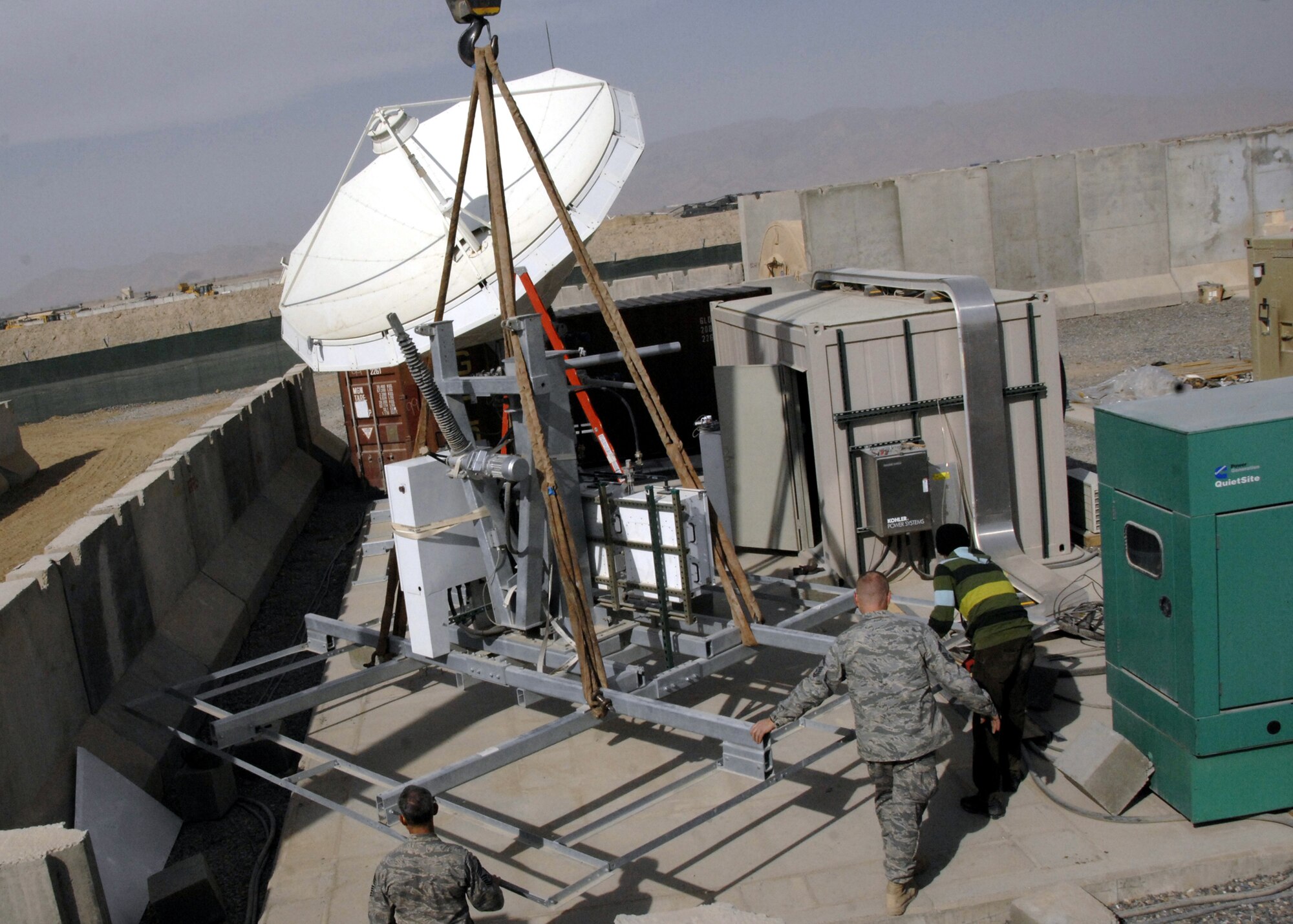 Airmen from the 451st Expeditionary Communications Squadron rotate a satellite dish load frame into its new position, Jan. 13, 2010. This was done as part of a theater-wide satellite realignment and provides redundancy as well as more bandwidth to the theater. This satellite allows for the availability of communications for U.S. Air Force personnel on Kandahar. (U.S. Air Force photo/Senior Airman Timothy Taylor/Released)