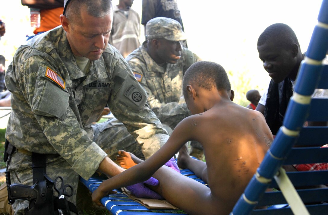 U.S. Army Capt. Buddy Davis, a physician’s assistant, treats a small boy for a leg injury at the forward operating base set up by the 82nd Airborne Division's 1st Squadron, 73rd Cavalry Squadron in Port-au-Prince, Haiti Jan. 18, 2010. The squadron does not have the supplies to establish a clinic, but is seeing patients brought to the FOB with the supplies they have. They are looking for additional medical resources such as clinics or hospitals in the area to refer the more critical patients.