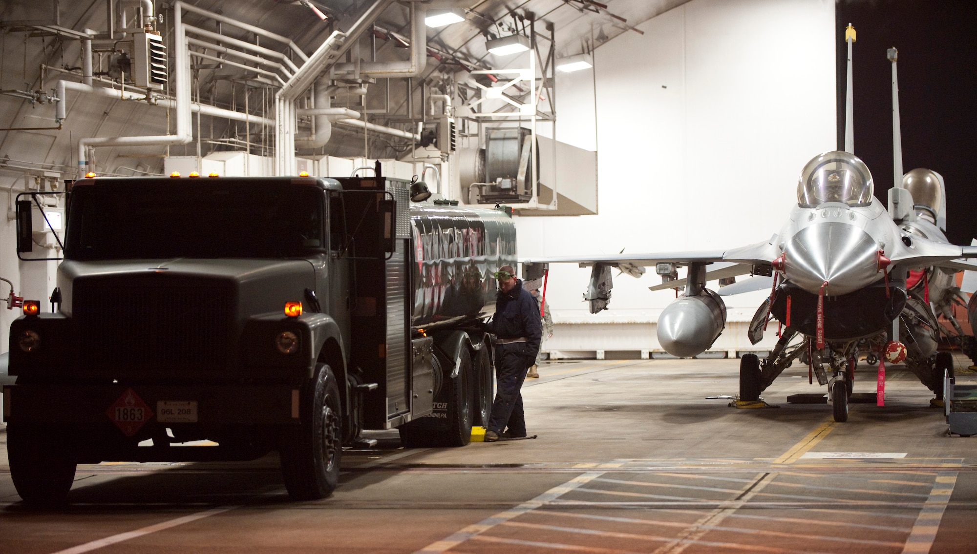 MISAWA AIR BASE, Japan -- Staff Sgt. Curtis Skaggs, 14th Aircraft Maintenance Unit crewchief, places chalks behind the tires of an R-11 fuel truck in a hardened aircraft shelter Jan. 19. Safety of personnel and equipment is a top priority on the flightline, and the mandatory chalks help prevent vehicles such as this from accidentally rolling. (U.S. Air Force photo/Staff Sgt. Samuel Morse)