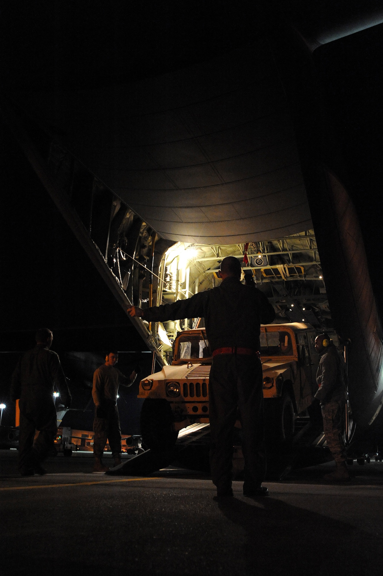 U.S. Air Force Tech. Sgt. Charles Moore, 41st Airlift Squadron loadmaster stationed at Little Rock Air Force Base, Ark., gives directional adjustments to an 82nd Airborne Humvee driver to ensure no damage is done to the C-130J Hercules or the Humvee during loading at Pope Air Force Base, N.C., Jan. 19, 2010. A Humvee loaded into the back of a C-130J has approximately one to two feet of clearance from the walls of the aircraft to the fame of the vehicle. Little Rock AFB is a component of Air Mobility Command. Since Jan. 13, AMC has delivered more than 1,600 tons of supplies to the region as part of Operation Unified Response. AMC aircraft and personnel continue to support the international effort to increase the velocity with which aid is flowing to those in need. (U.S. Air Force photo/Staff Sgt. Chad Chisholm) 