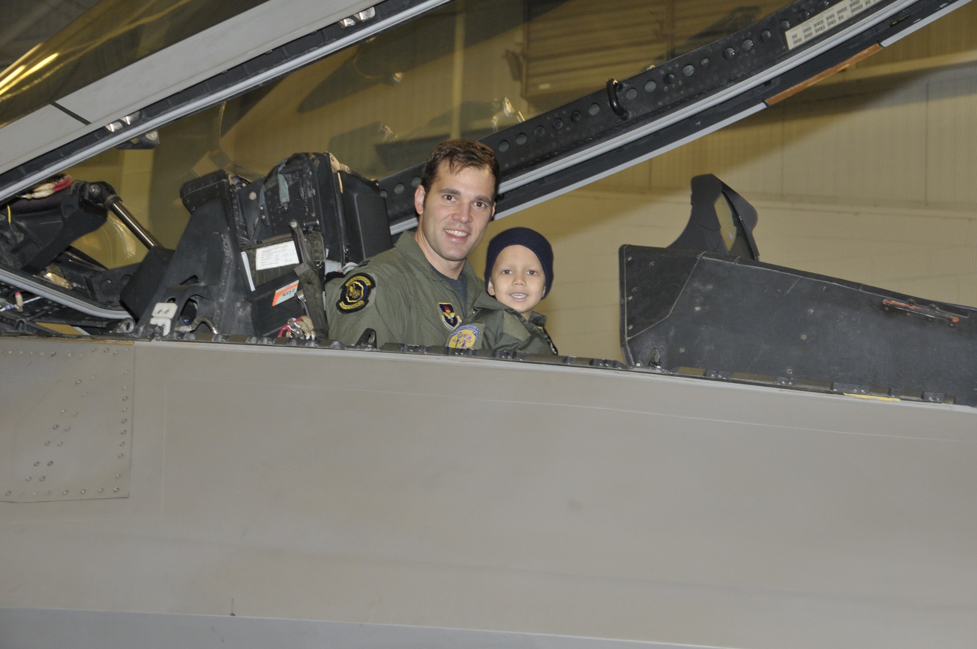 Capt. John Hensz, 43rd Fighter Squadron Instructor Pilot, sits with Dylan Hardee, a child in the Make-A-Wish program, in the cockpit of an F-22 Raptor.  (U.S. Air Force photo/Lisa Norman)