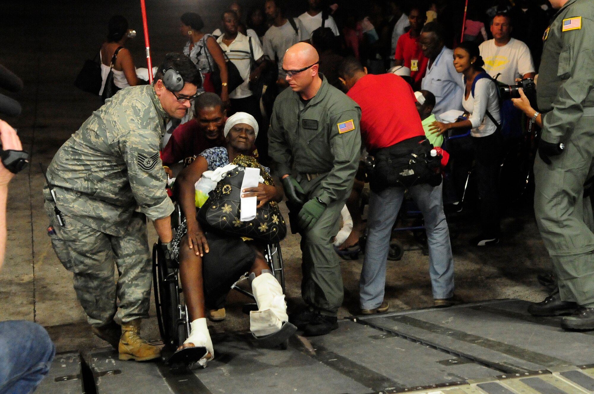 Airmen assist Haitian evacuee Leanne Civil onto a McChord C-17 in Port-Au-Prince, Haiti Sunday. Approximately 186 Haitians were evacuated to Orlando, Fla. from Toussaint L’Ouventure International Airport in Haiti. (U.S. Air Force photo/Master Sgt. Chris Haylett)