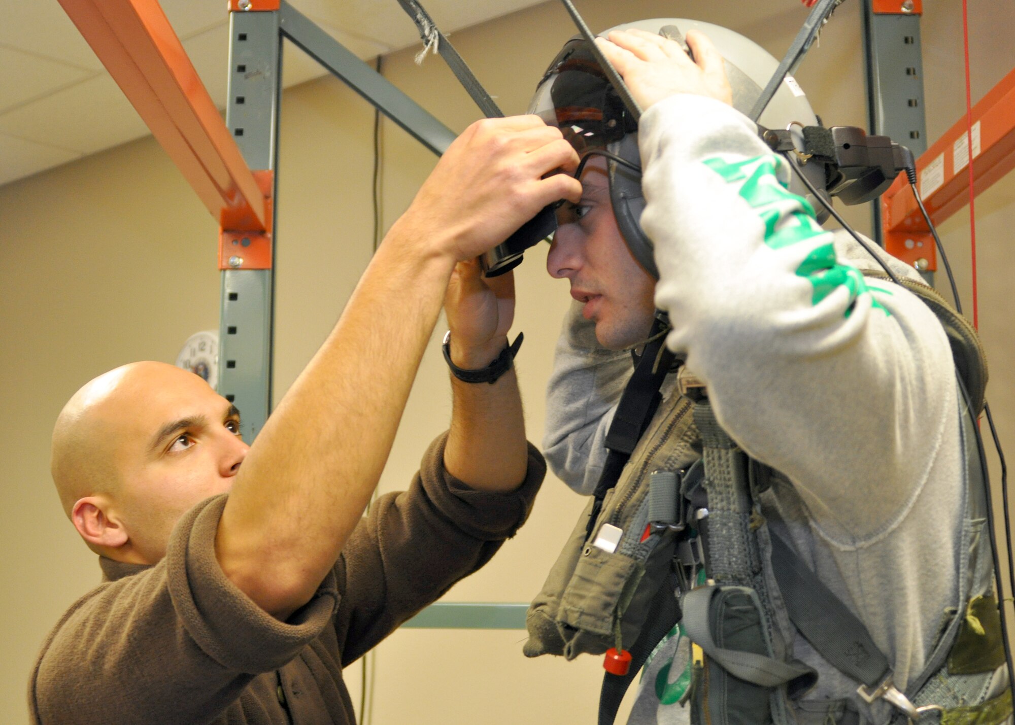 Senior Airman Paul Navarro, an aircrew flight equipment technician in the 917th Operational Support Squadron at Barksdale Air Force Base, La., adjusts the helmet of Brian Crowe, a civilian contractor working out of Claiborne Range as he prepares to simulate a parachute landing during a base tour on Jan. 13, 2010. Claiborne Range, located three hours South of Barksdale, is an air-to-ground gunnery range used by the 47th Fighter Squadron for A-10 Thunderbolt II training. The base tour gave the contractors a chance to see Barksdale’s aircraft and peek into the life and training of pilots. (U.S. Air Force Photo/Senior Airman Crystal Marie Jordan)