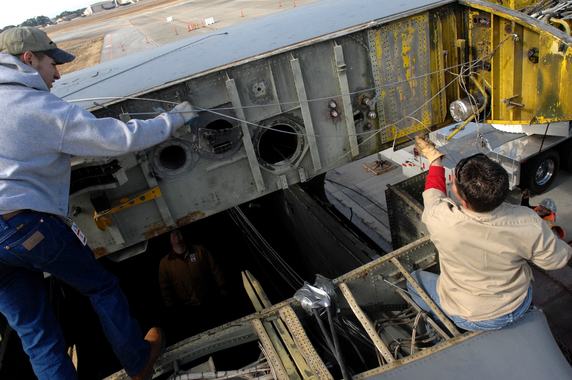 Tony Smith, left, a contractor with SIMAIR and Sean Hofhine, right, a contractor with Southwest Industrial Rigging, prep a wing as it is lowered on to a C-130E fuselage outside the 19th Special Operations Squadron at Hurlburt Field Jan. 14. The aircraft will be used as a simulator for ground, loading and maintenance training beginning in March. (U.S. Air Force photo by Senior Airman Matt Loken)