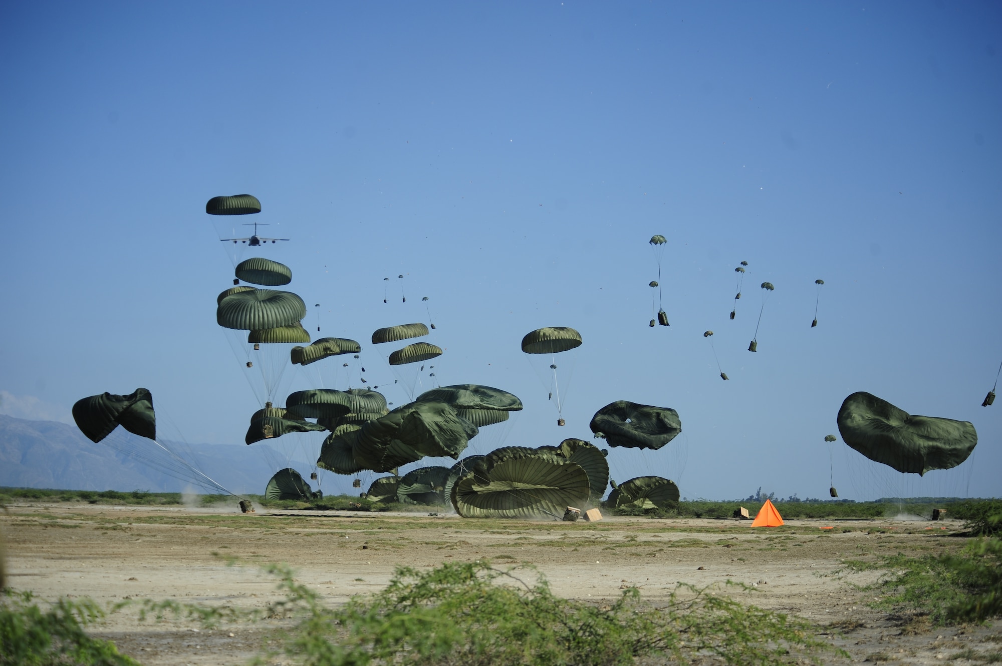 An Air Force C-17 Globemaster III aircraft airdrops humanitarian aid into the outskirts of Port-au-Prince, Haiti, Jan. 18, 2010. The air delivery mission was conducted by a Charleston Air Force Base C-17 and an aircrew with the base's 16th Airlift Squadron as test to determine if future air delivery missions would be possible. (U.S. Air Force photo by Tech. Sgt. James L. Harper Jr./Released)