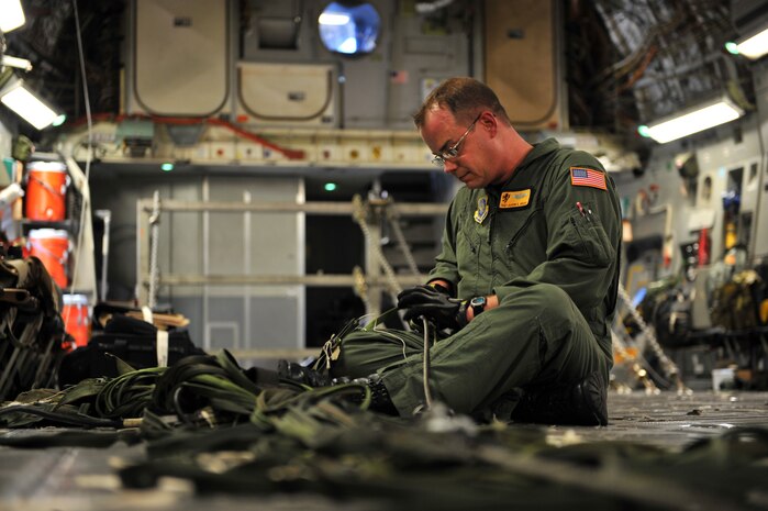 Air Force Tech. Sgt. Aaron Avery works with chute anchor cables on his C-17 Globemaster III cargo aircraft after pallets of relief supplies exited his aircraft over Haiti Jan. 18, 2010. The C-17, crewed by Airmen from the 437th Airlift Wing at Charleston Air Force Base, S.C., departed Pope AFB, N.C., and delivered 40 pallets of food and water. The mission was the first of its kind during Operation Unified Response to test the feasibility of providing supplies through air delivery. (U.S. Air Force photo by Master Sgt. Shane A. Cuomo/Released)