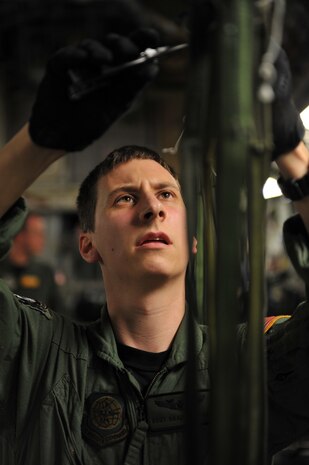 Air Force Staff Sgt. Brad Edwards disconnects static lines aboard a C-17 Globemaster III cargo aircraft after pallets of relief supplies exited his aircraft over Haiti Jan. 18, 2010. The C-17, crewed by Airmen from the 437th Airlift Wing from Charleston Air Force Base, S.C., departed Pope AFB, N.C., and delivered 40 pallets of food and water. The mission was the first of its kind during Operation Unified Response to test the feasibility of providing supplies through air delivery. Sergeant Edwards is a loadmaster with the 16th Airlift Squadron at Charleston AFB. (U.S. Air Force photo by Master Sgt. Shane A. Cuomo/Released)