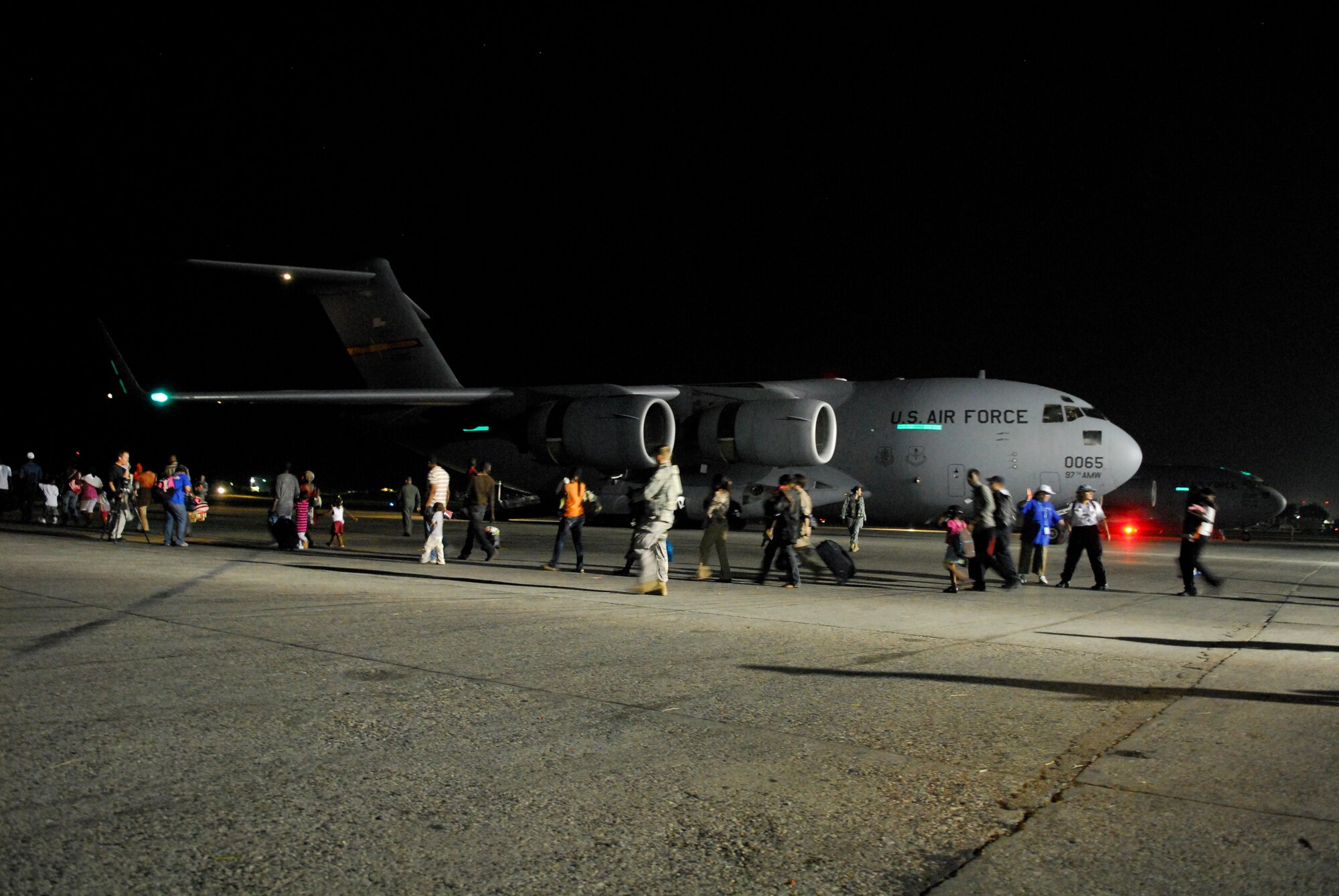 Citizens, escorted by Air Force personnel and international aid workers, traverse the flight line enroute to a C-17 cargo aircraft at the Toussaint Louverture International Airport in Port-au-Prince, Haiti, Jan. 19.  The C-17, which can carry multiple vehicles or up to 40 pallets of supplies, was used as a passenger aircraft for the hour and a half trip to Orlando, Fla.  (U.S. Air Force photo/1st Lt. Matt Schroff)