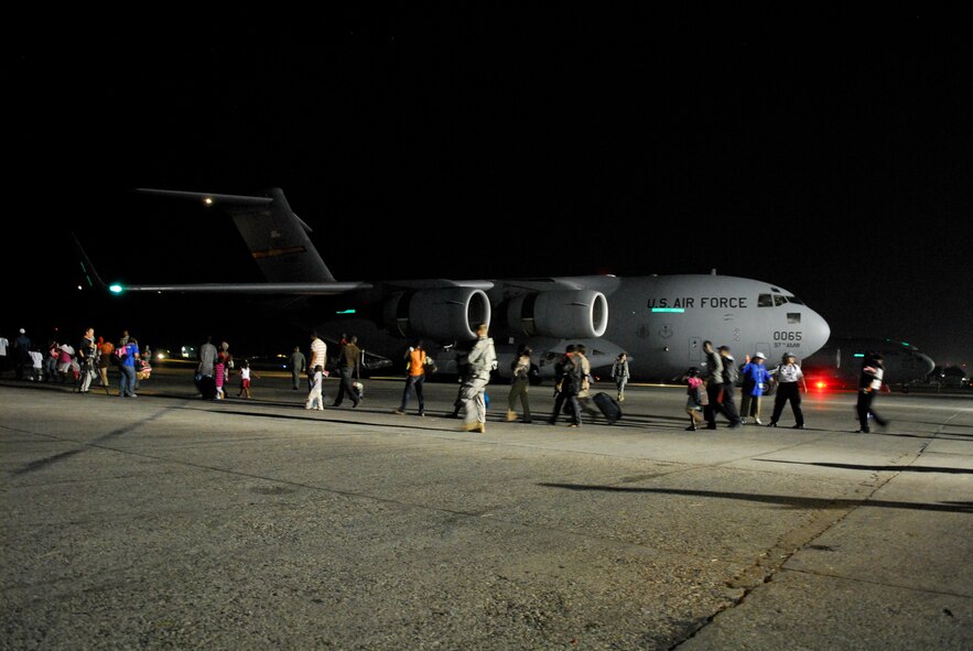 Citizens, escorted by Air Force personnel and international aid workers, traverse the flight line enroute to a C-17 cargo aircraft at the Toussaint Louverture International Airport in Port-au-Prince, Haiti, Jan. 19.  The C-17, which can carry multiple vehicles or up to 40 pallets of supplies, was used as a passenger aircraft for the hour and a half trip to Orlando, Fla.  (U.S. Air Force photo/1st Lt. Matt Schroff)